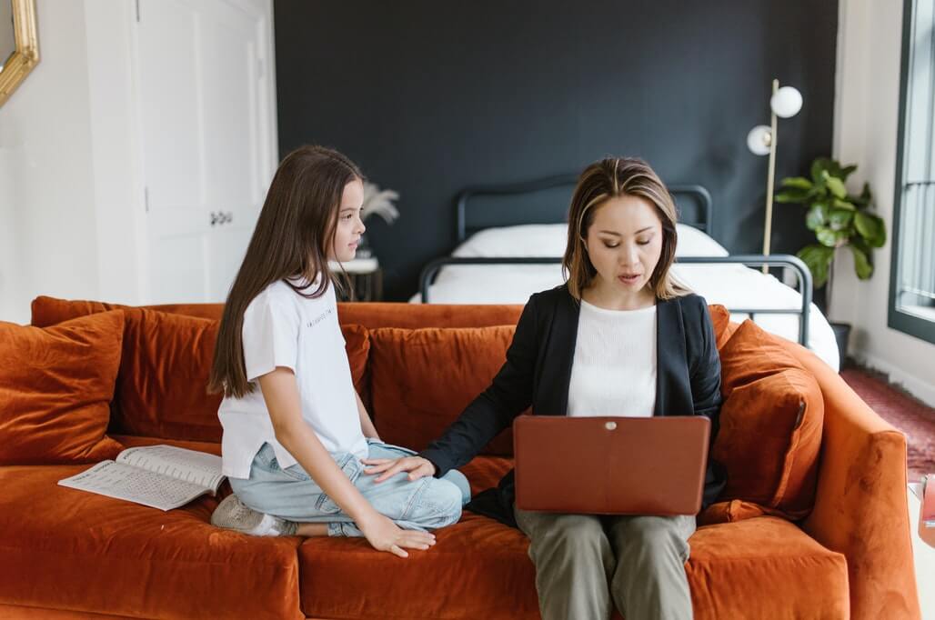 mom is showing an example to her kid by dressing up nicely while working remotely
