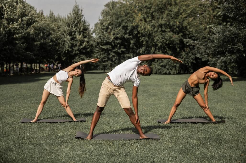 three people stretching in the park
