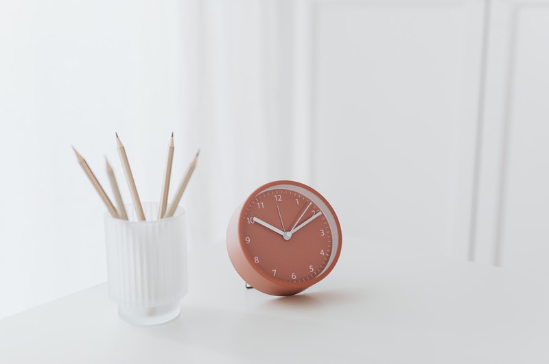 pink clock and a jar with pencils besides