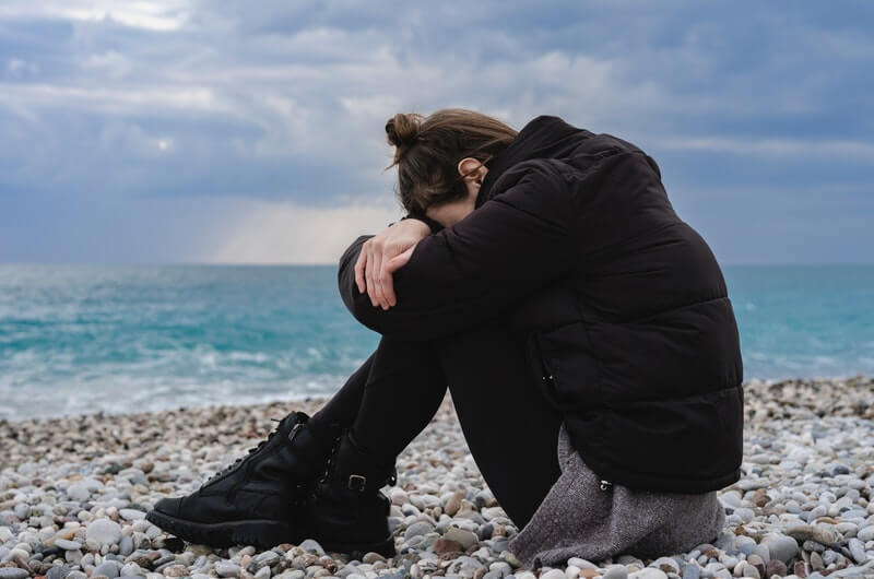 person sitting on pebbles and thinking about her priorities